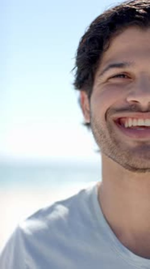 Vertical video: Smiling man enjoying sunny day at beach, close-up of face and teeth