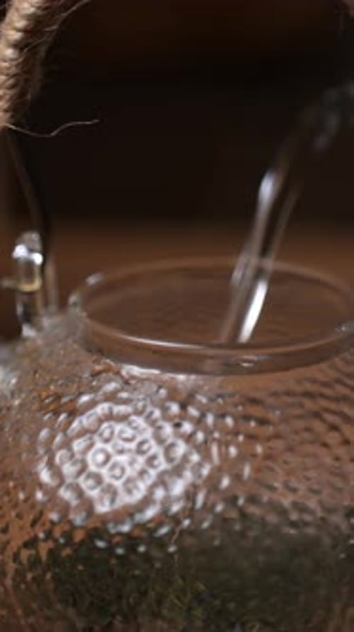 Water Being Poured Into Glass Teapot