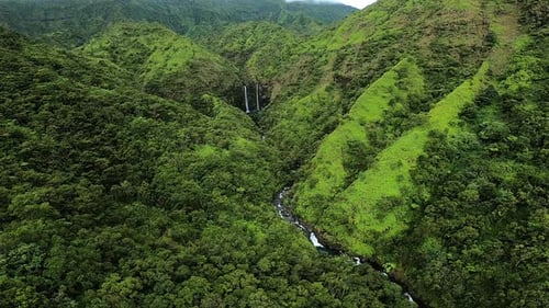 Aerial View of Waterfall in Rolling Hills and Green Landscape in Kauai Hawaii