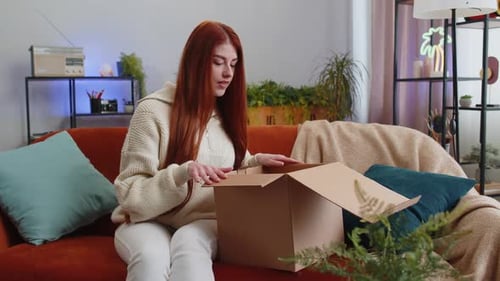 Happy Young Woman Shopper Unpacking Cardboard Box Delivery Parcel Online Shopping Purchase at Home