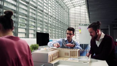 Group of Young Architects with Model of a House in Office, Talking