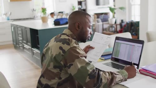 African american father with son sitting at table and working