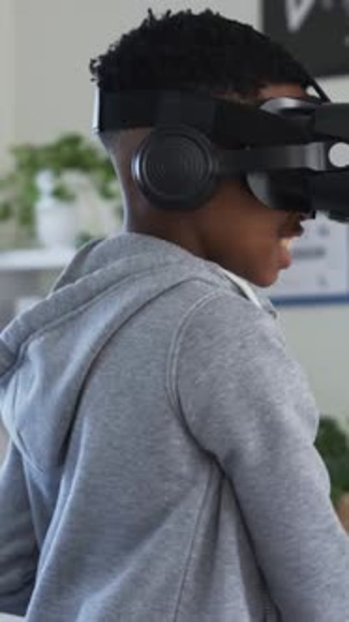Vertical video: VR headset starting, student in grey hoodie, striped tee grabbing item in class