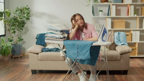 Woman Looks Bored While Ironing Clothes Indoors