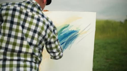 Back View of Illustrator Painting on Large Canvas in a Tranquil Field