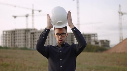 Man Construction Engineer Wearing Glasses Masterfully and Deftly Puts on Helmet