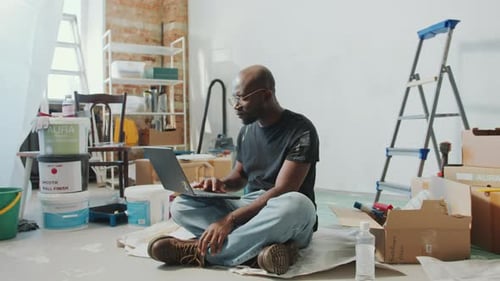 Man uses Laptop in Renovation Setting