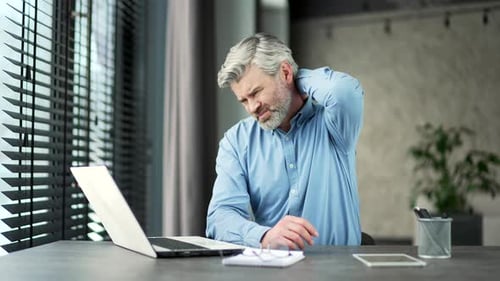 Man Massaging Stiff Neck in Office Environment