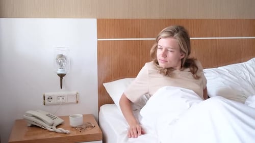 Young Woman Wakes Up and Stretches in Bed