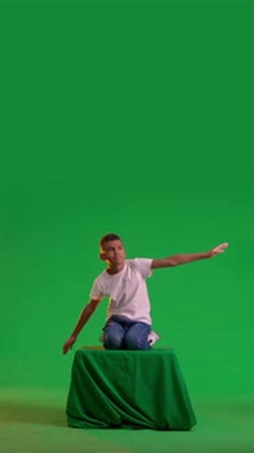 Playful Schoolboy Flying on a Green Box at a Green Screen