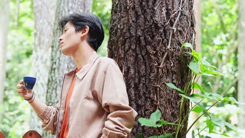 Thoughtful young asian man enjoying coffee break at cafe nature