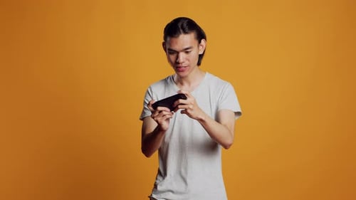 Modelo masculino feliz jogando Vídeo no smartphone