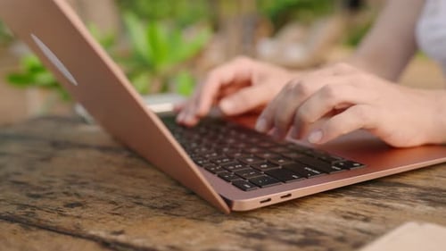Hände einer jungen Frau, die im Café am Meer im Freien auf dem Laptop programmiert, Freiberuflerin tippt am Computer