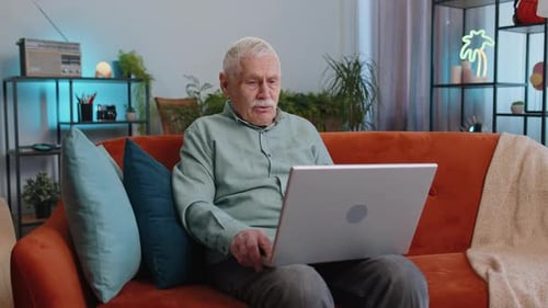 Senior Man Using Laptop for Video Call at Home