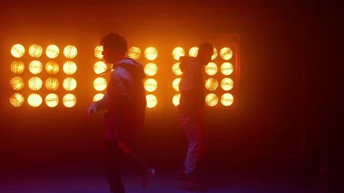 Male Dancers Performing in Dark Studio with Bright Lights