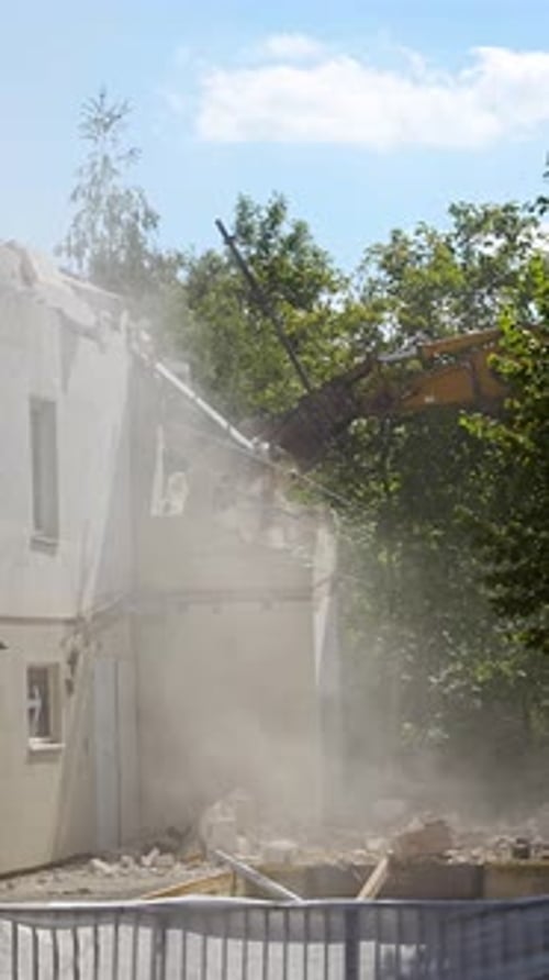 Demolition Excavator Using Hydraulic Jaws to Dismantle a Concrete Building at a Construction Site