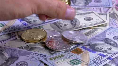 La main place les pièces cryptées de différentes devises sur une table avec des dollars américains