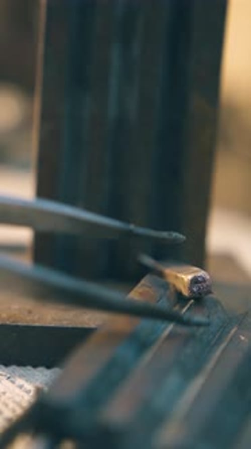 Jeweler Takes Gold Bar with Tweezers on Table Close View