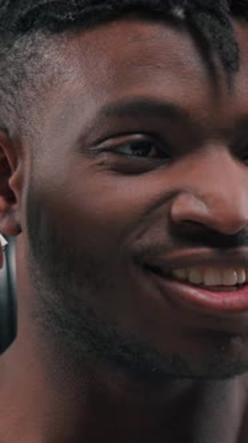 Smiling Young Man Inserts Wireless Earbud