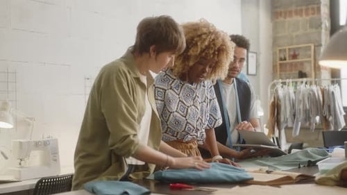 Designer Discussing Sketches with Seamstresses in Dressmaking Studio