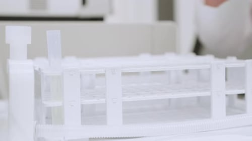 Gros plan d'une femme insérant des tubes dans un collecteur de fractions connecté à un système HPLC
