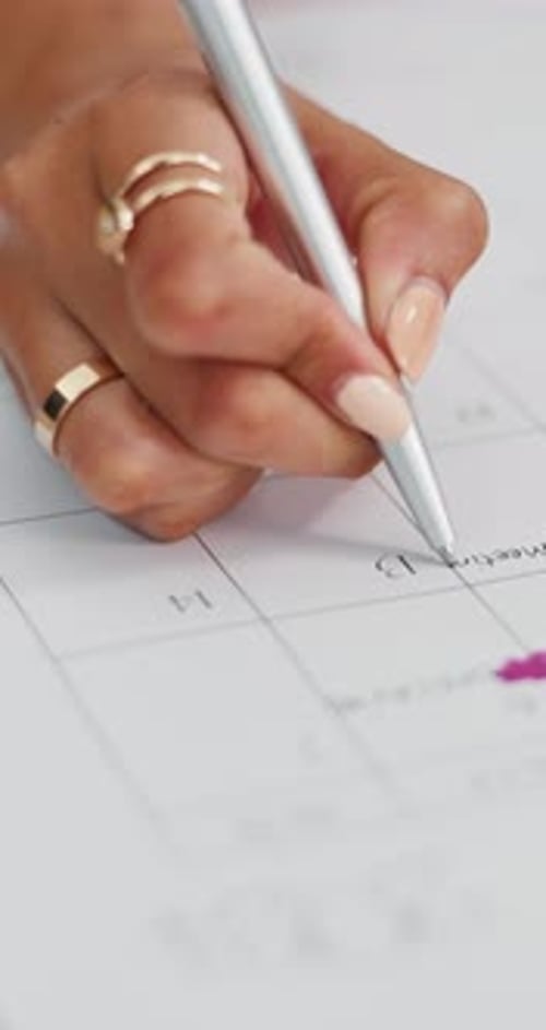Woman writes on a Calendar Page in bright light