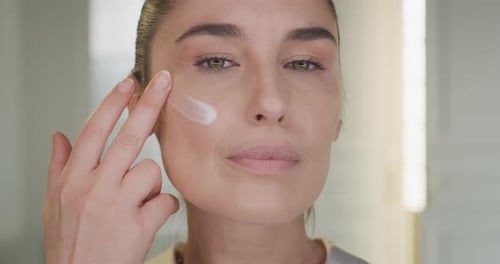 Woman Applying Cream to Her Face, Close Up
