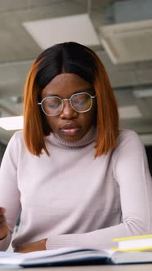 Young Adult Writing in Notebook at Desk