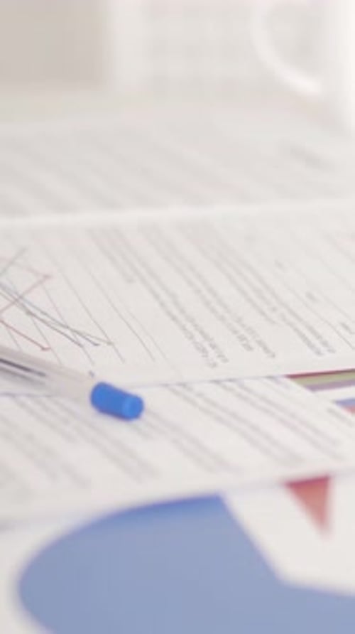 Graphs and Pen on Table in Bright Workplace