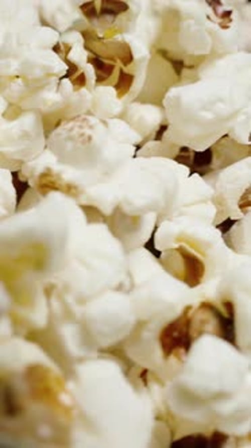 Vertical video. A pile of popcorn rotates in close-up.