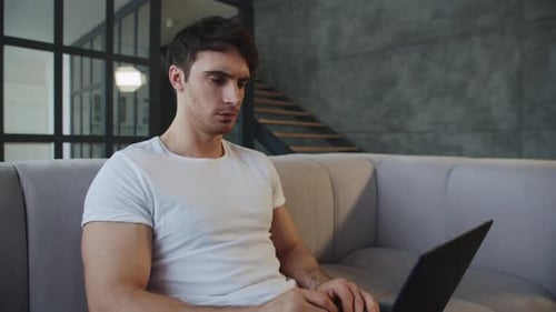 Concentrated man working on laptop computer at home