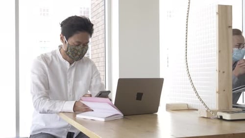 Men work at desk with protective dividers and masks