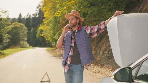 Caucasian Stressful Young Worried Man Talking on Phone Near Broken Car Car Breakdown Incident