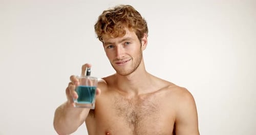 Handsome Man Sprays Cologne Smiling in Studio