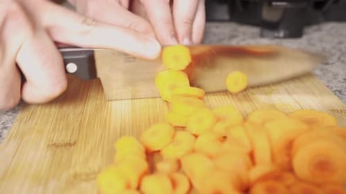Person Slicing Fresh Carrots on Cutting Board