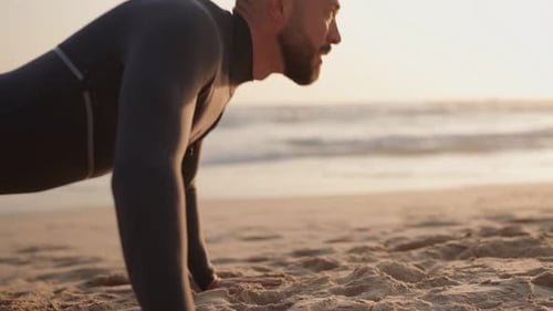 Fit Man Doing PushUps on Sandy Beach at Sunset