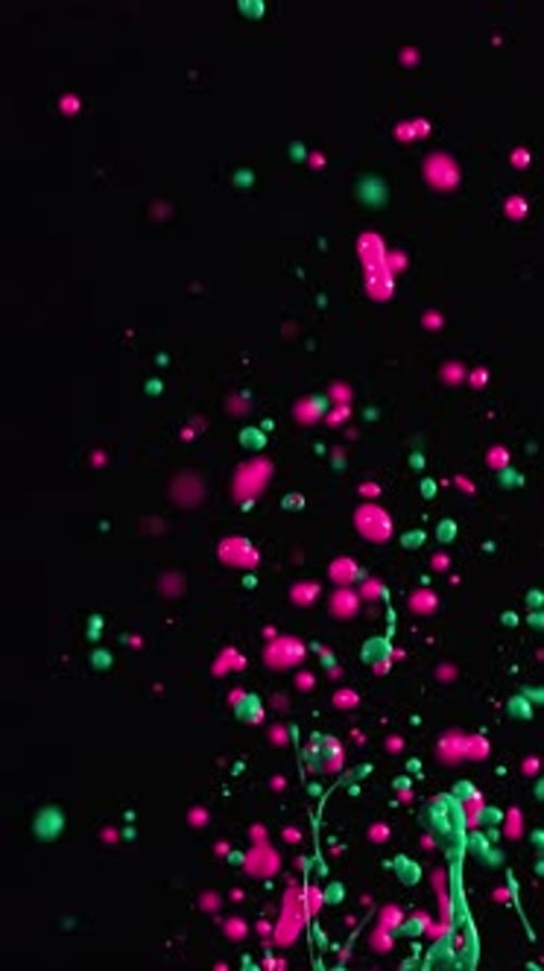Pink And Green Paint Splattering In Slow Motion On Dark Background