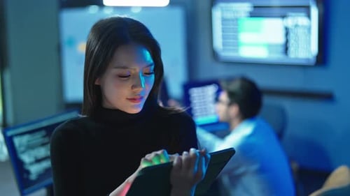 Female Developer Using Tablet In Dark Technology Office