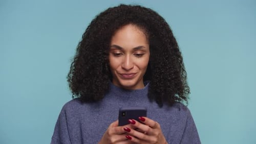 Woman Smiles, Surprised by News on Mobile Phone