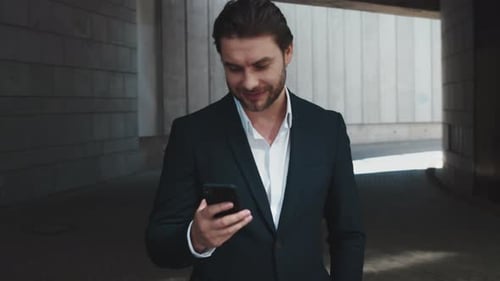 Successful businessman smiling and using smartphone in the city street outdoors