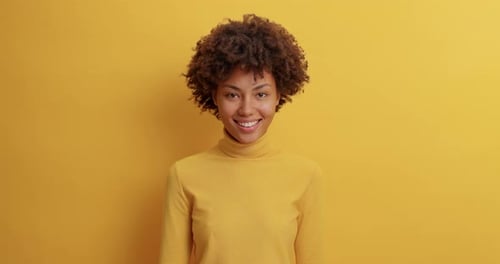 Smiling woman in yellow against yellow backdrop
