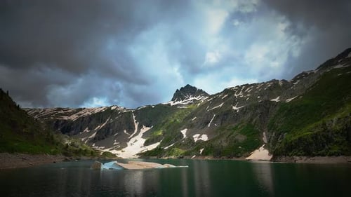 Time Lapse Of Alpine Lake With Clouds And Block Of Last Snow