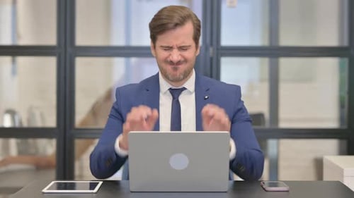 Man in Suit with Headache Works on Laptop