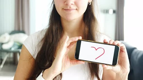 Woman Holding Phone with Heart Drawing Displayed