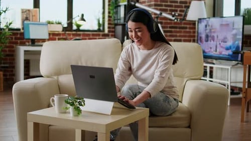 Woman on Couch Using Laptop with Headphones