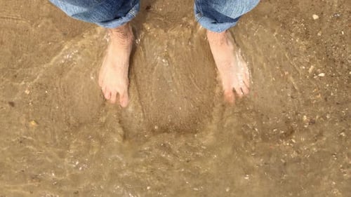 mans legs walking on golden sand beach