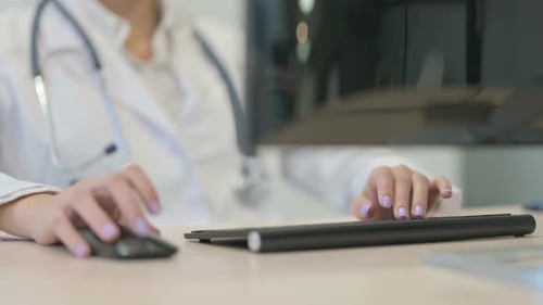 Close up of Young Female Doctor Working on Desktop Computer in Clinic