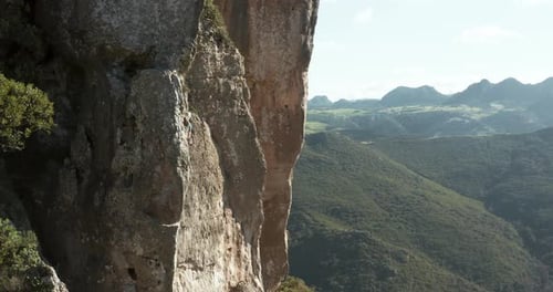 Male Rock Climber Clipping Rope On Sport Route On Cliff. revealing drone shot