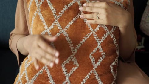 Woman with Hands on Orange Pillow Indoors