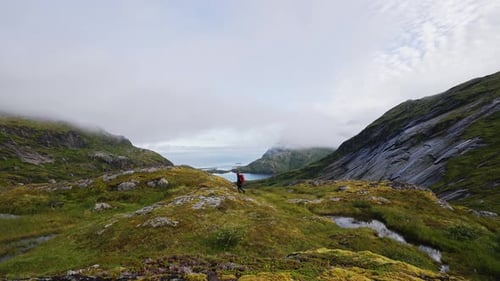 Tourist with a Backpack on Top and Looking at the Landscape on the Way to the Top of Manken Mountain